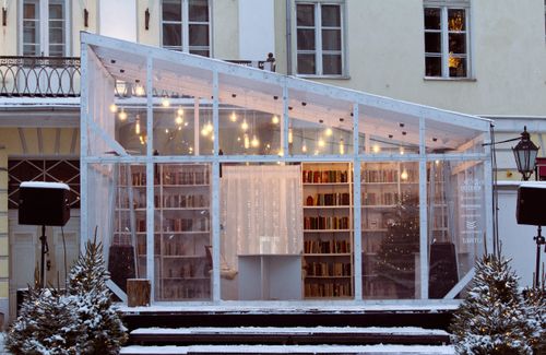 Free A serene glass house library decorated with string lights in a snowy winter setting. Stock Photo