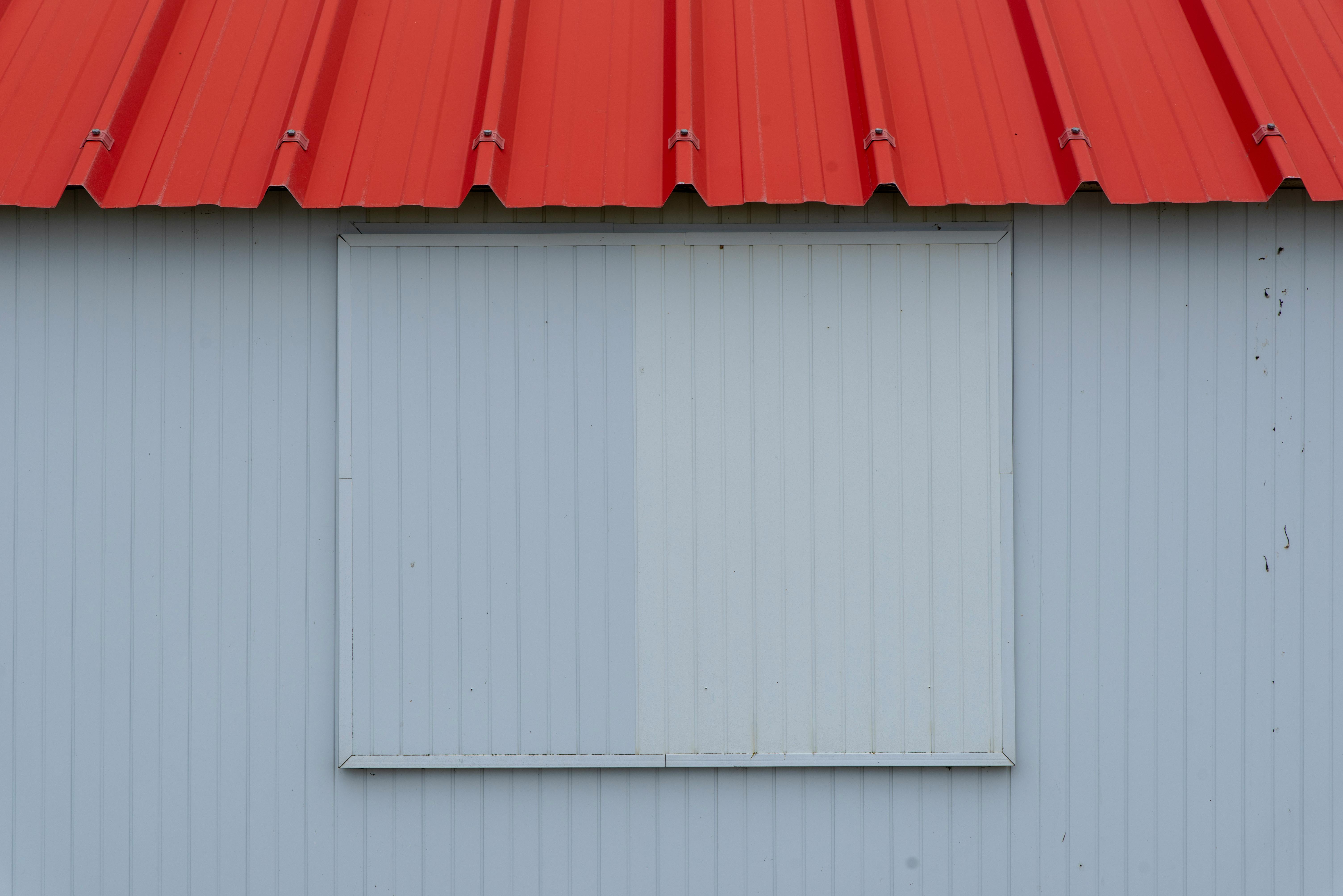 grátis Imagem minimalista de um telhado de metal vermelho com parede de painéis ondulados em tons de azul-acinzentado. Foto profissional