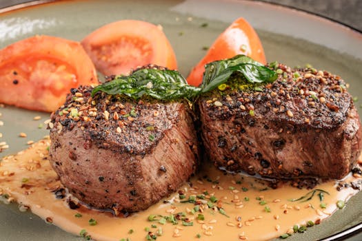 A gourmet pepper-crusted fillet served with fresh tomato slices and herbs.
