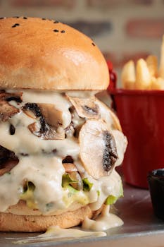 Close-up of a gourmet burger with mushrooms and fries on the side, perfect for food lovers.