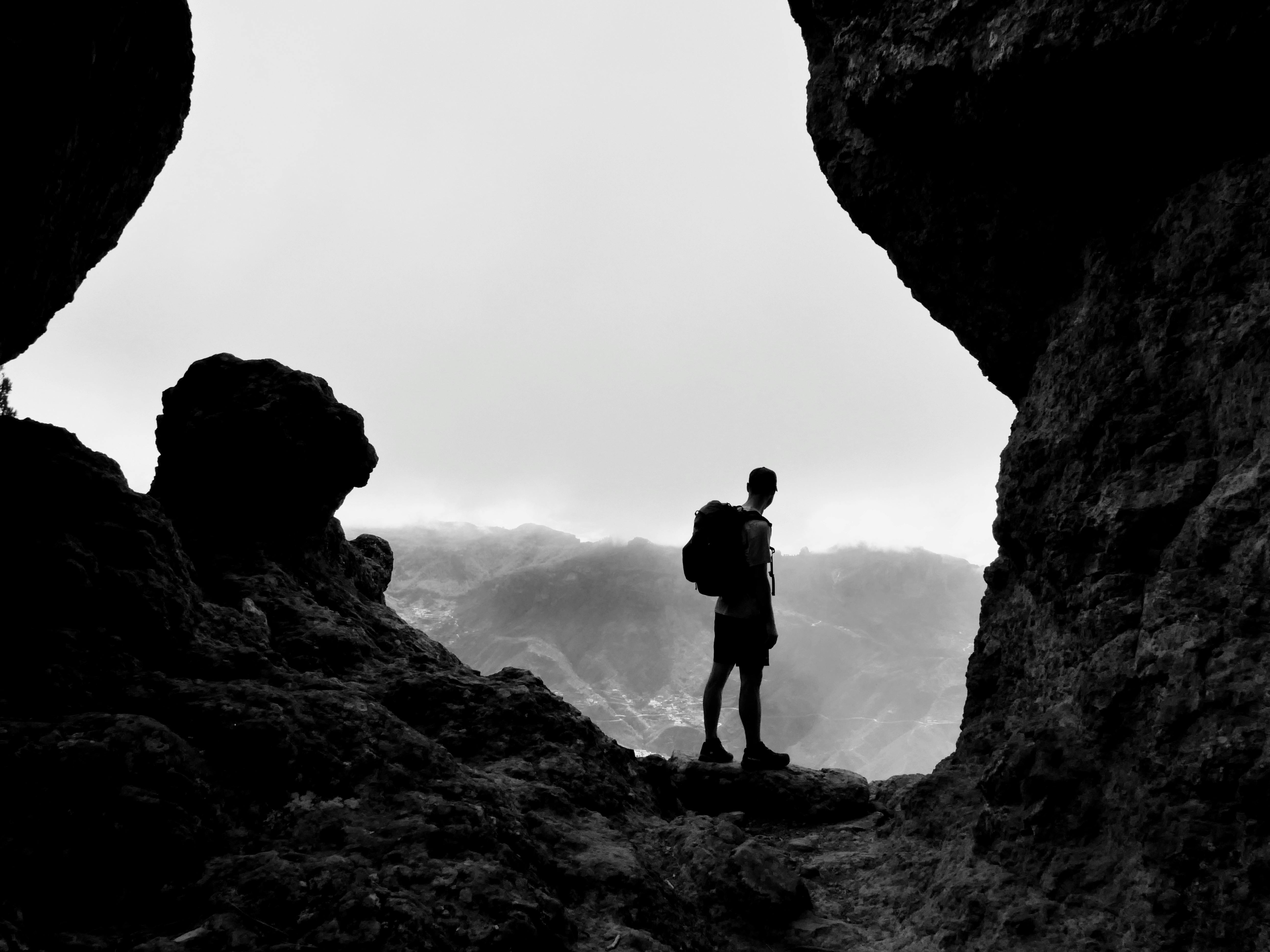 Silhouetted hiker with backpack on a dramatic cliff in Spanish landscape.