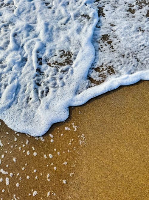 Free Gentle waves foaming on the sand, evoking a serene coastal vibe. Stock Photo