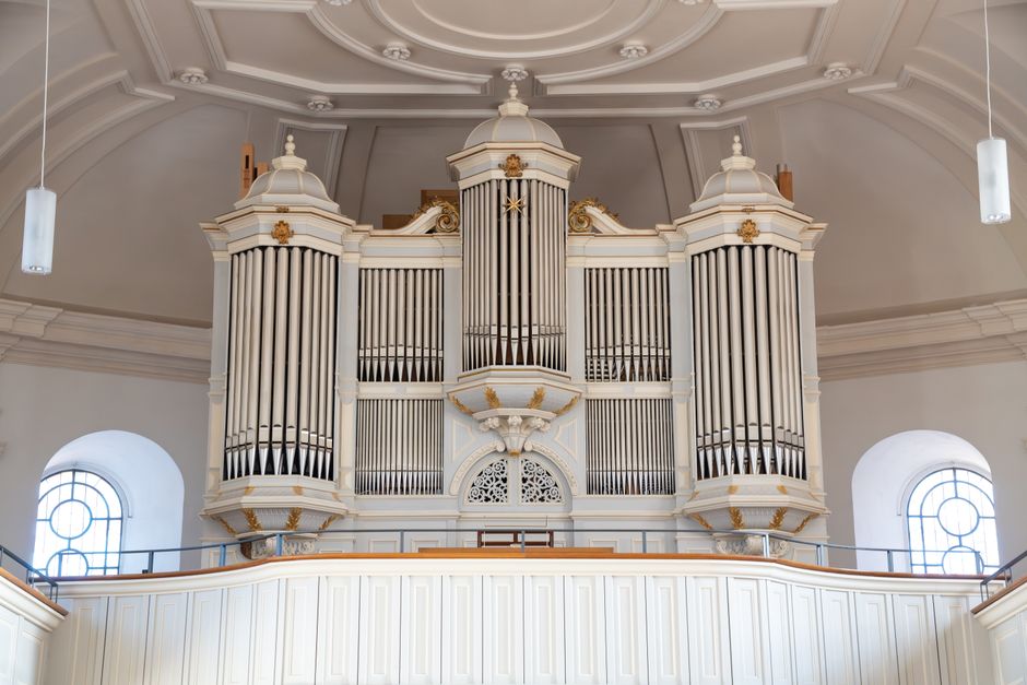 Majestic white pipe organ in a grand church interior with intricate design details and high ceilings.