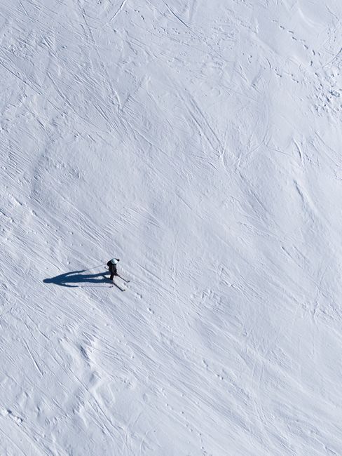 A lone skier navigates a steep snowy hill in this high-angle shot, epitomizing winter adventure.