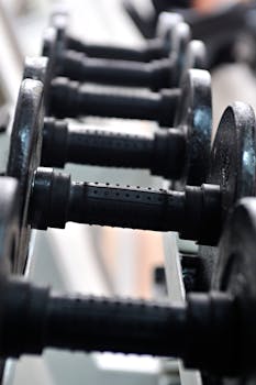 Detailed close-up of black dumbbells lined up in a gym setting, highlighting fitness and strength training.