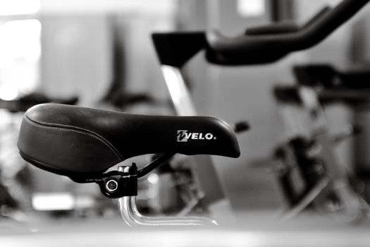 Detailed black and white shot of a gym bicycle saddle, highlighting fitness equipment aesthetics.