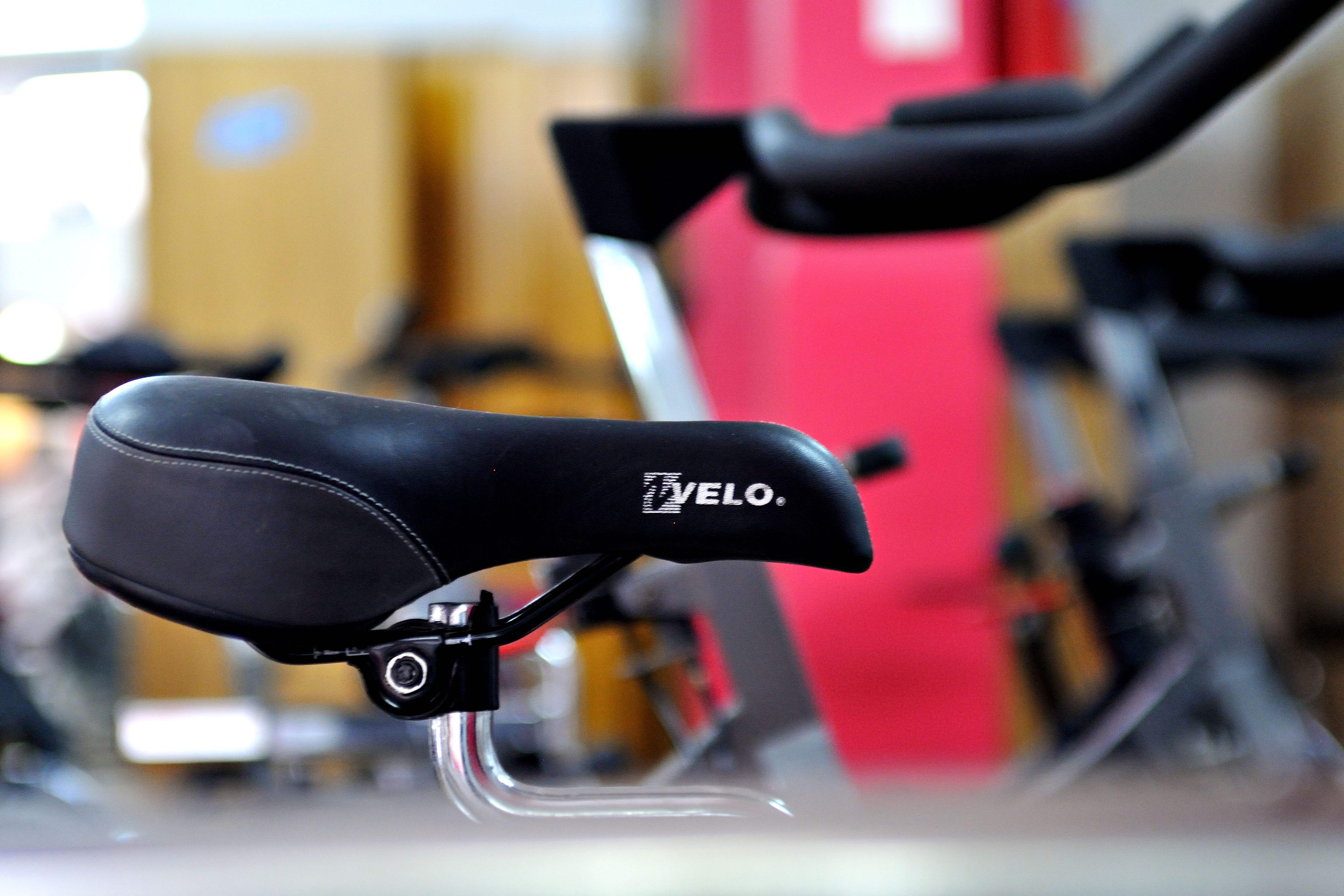 Close-up of a padded exercise bike saddle in a gym setting