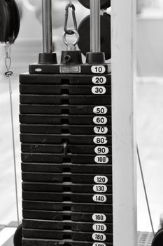 Monochrome view of a weight stack in a gym, showcasing various weight increments.