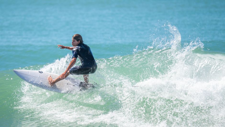 Dynamic mid-action shot of a surfer skillfully riding a wave in the ocean, capturing the essence of summer sports.