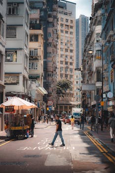 Daytime scene of a busy street in Hong Kong with pedestrians and urban environment.