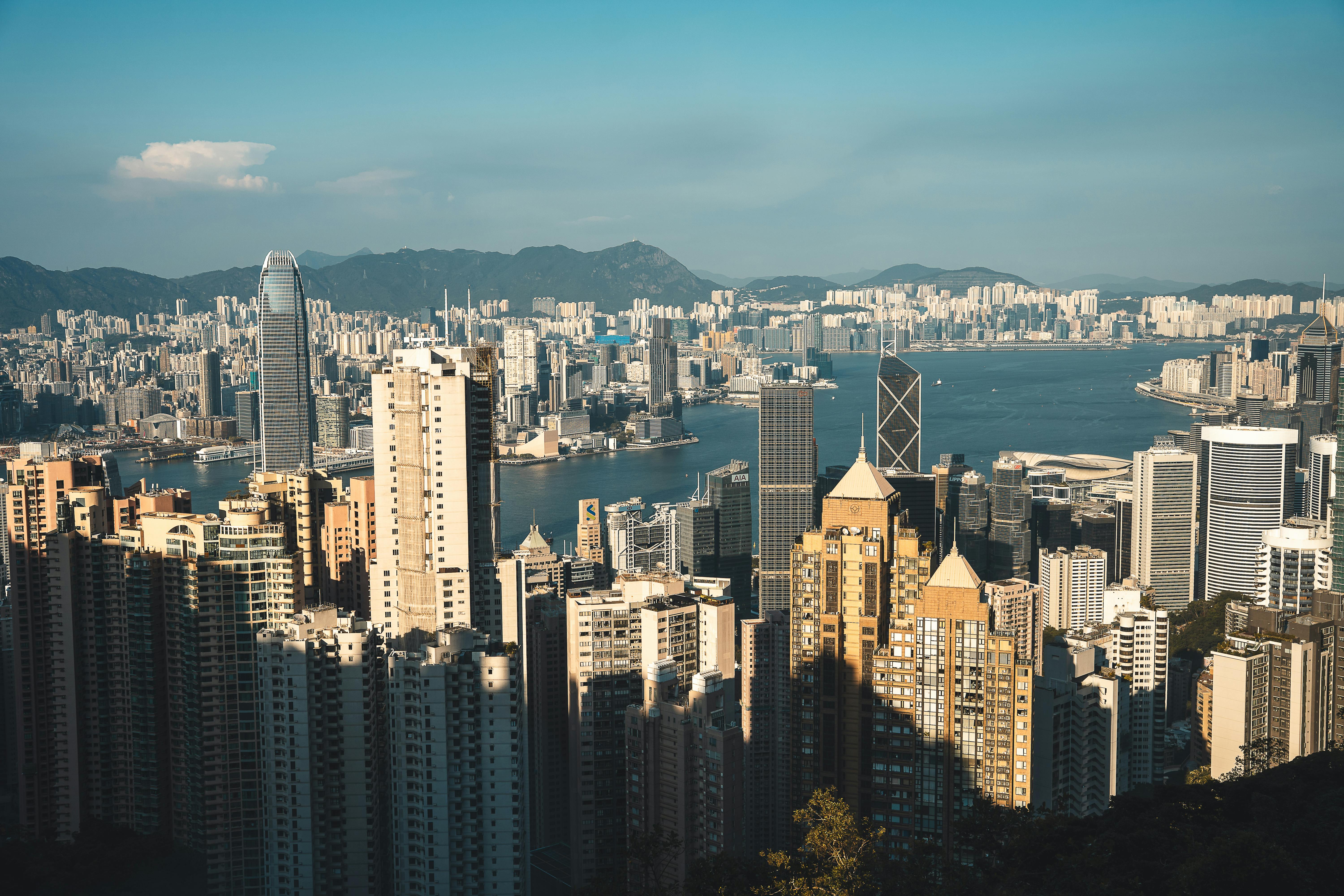 A breathtaking aerial view of Hong Kong's vibrant skyline and harbor under a clear sky.
