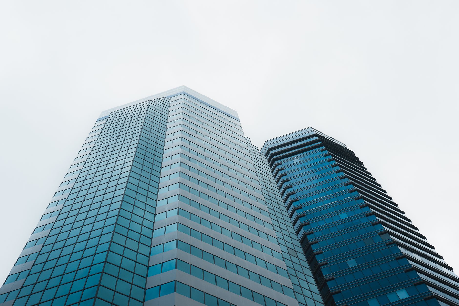 Low angle view of modern skyscrapers in Hong Kong against a cloudy sky, showcasing architectural design.