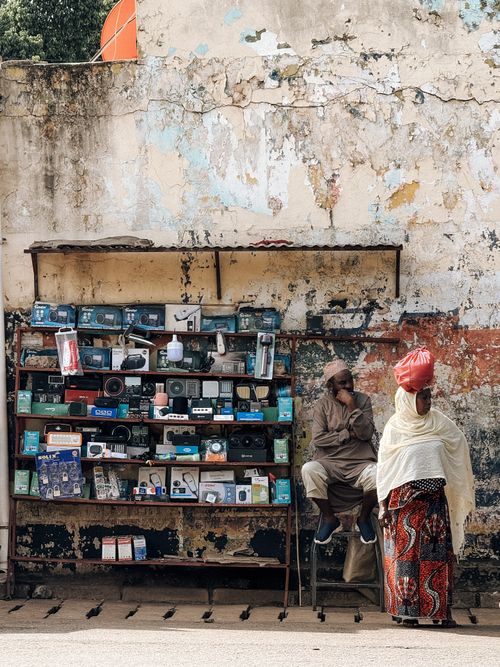Free A street vendor selling electronics against a weathered wall showcasing urban daily life. Stock Photo