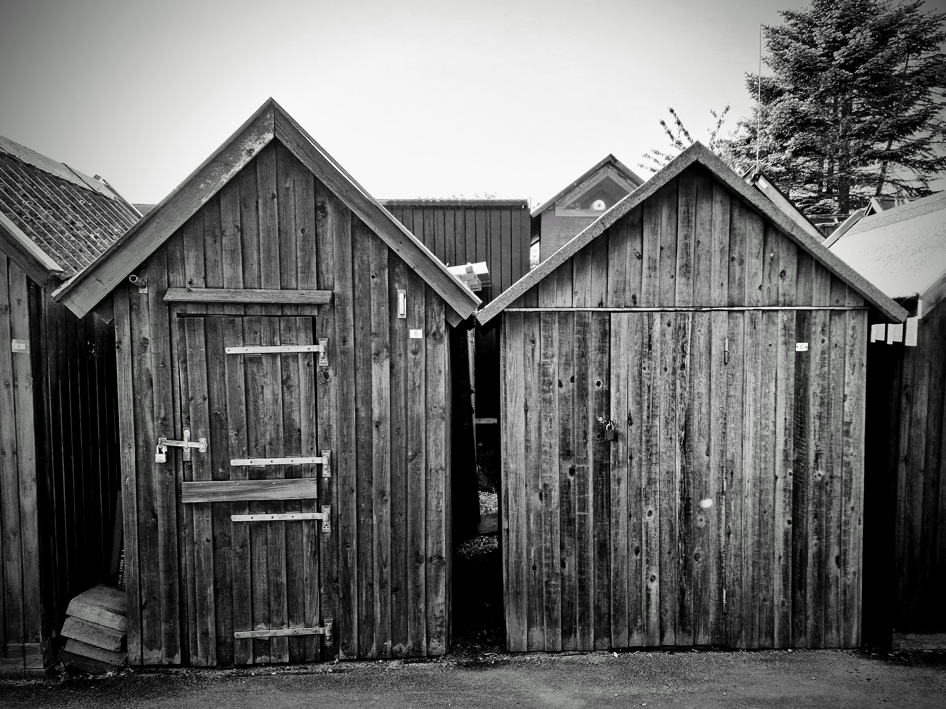 Two rustic wooden sheds captured in a black and white photograph, creating a vintage feel.