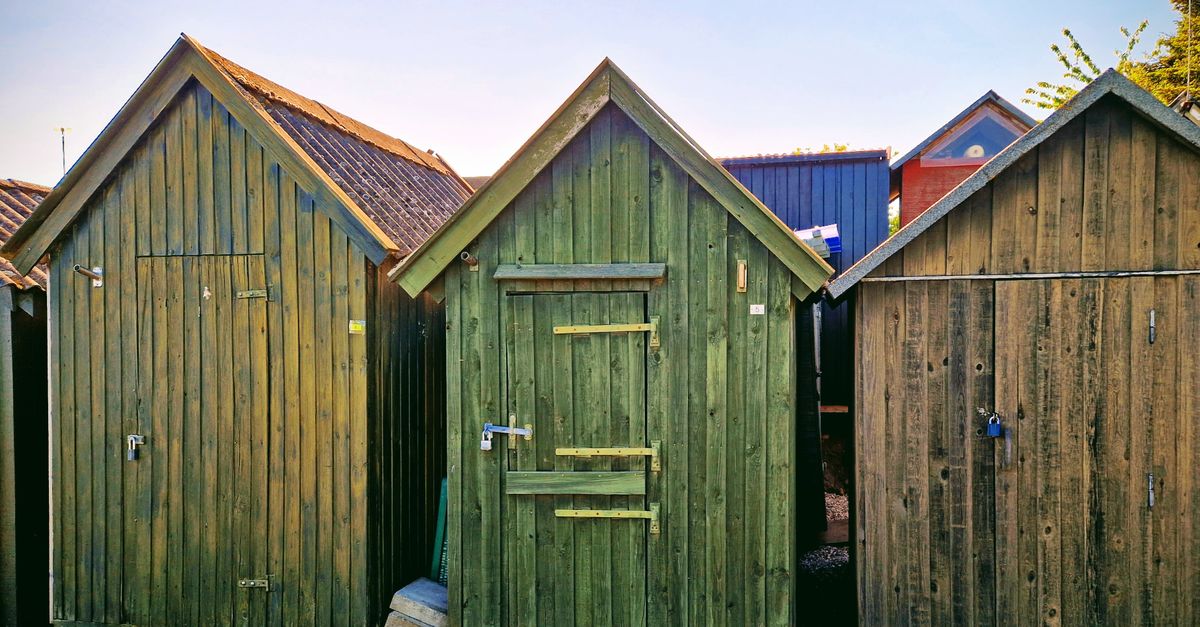Colorful wooden sheds in Assens, Denmark under clear summer sky.