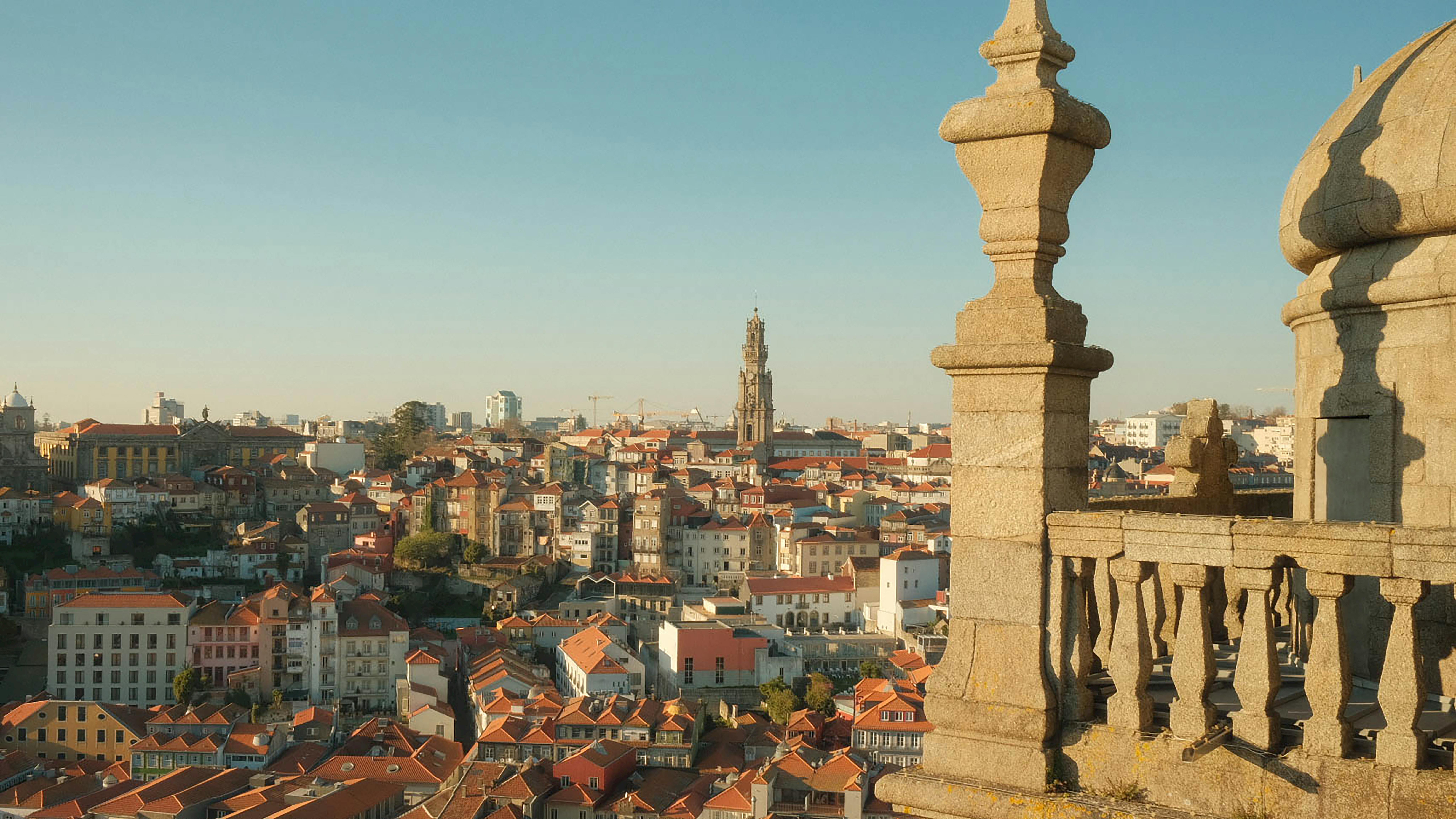 A picturesque view of Porto's cityscape featuring the iconic Clérigos Tower under a clear sky. - Coímbra