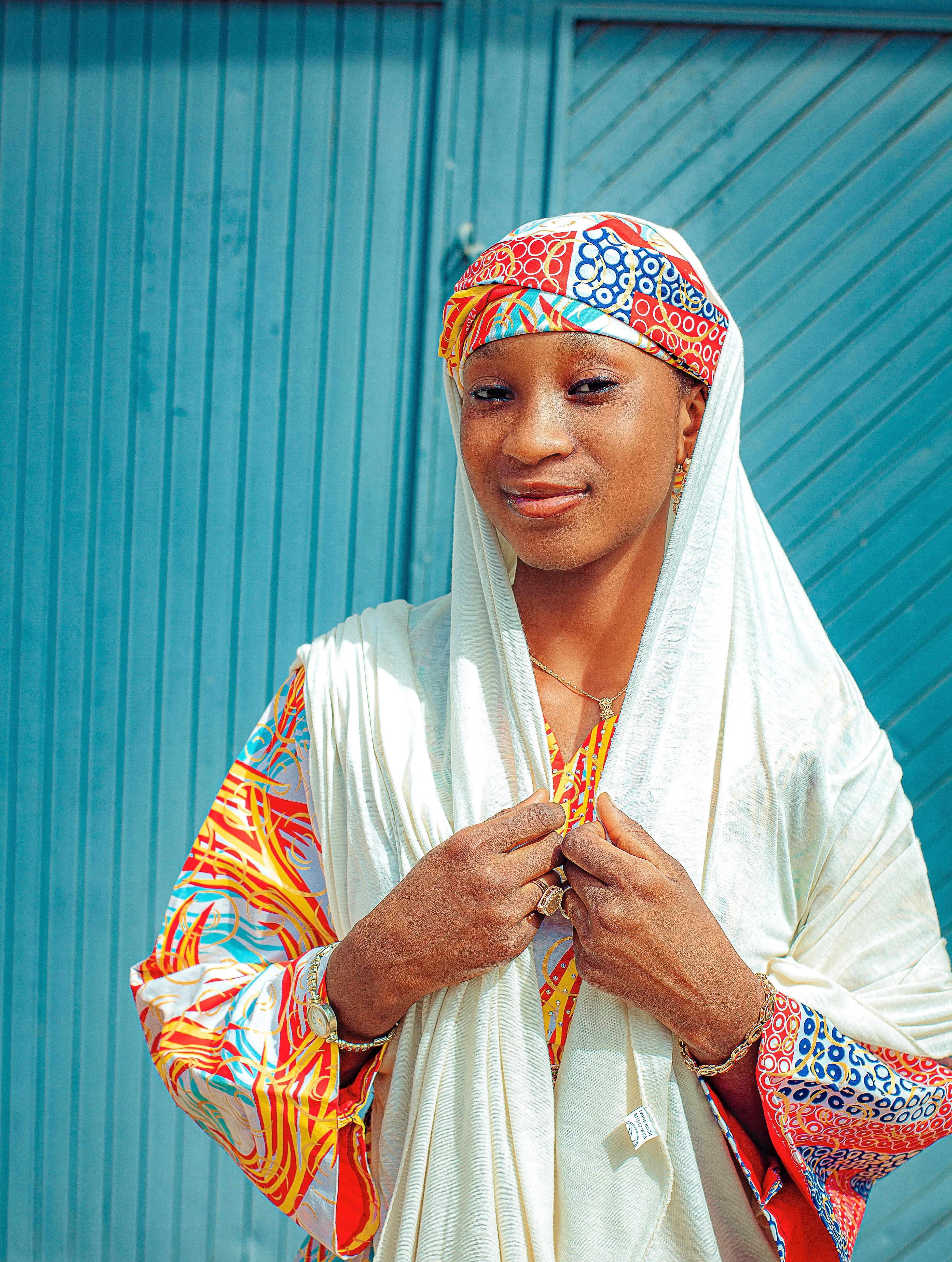 Smiling woman in colorful, traditional clothing against blue backdrop.