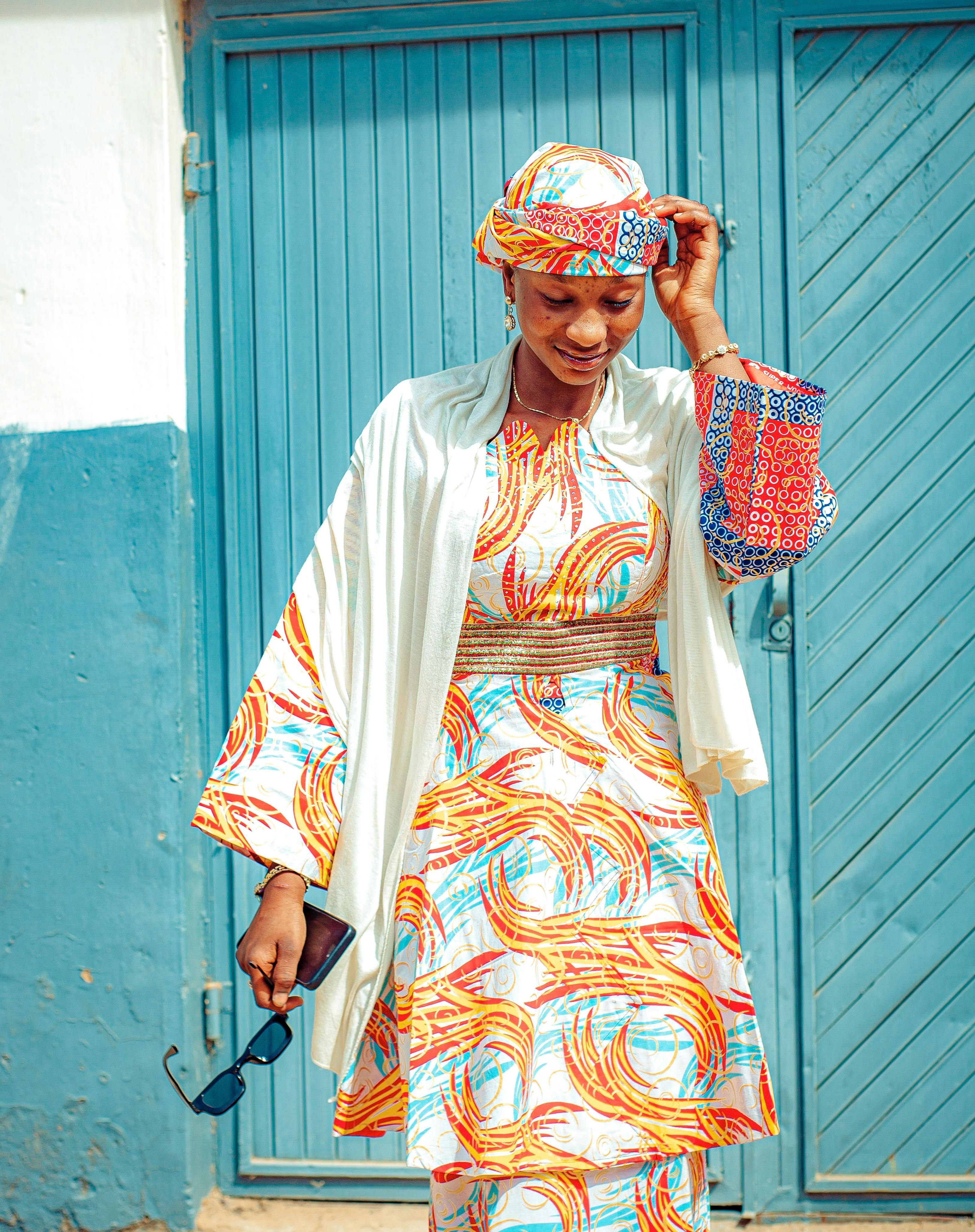 De franc Dona amb un vibrant vestit africà, un mocador al cap a joc i ulleres de sol. Foto d'estoc