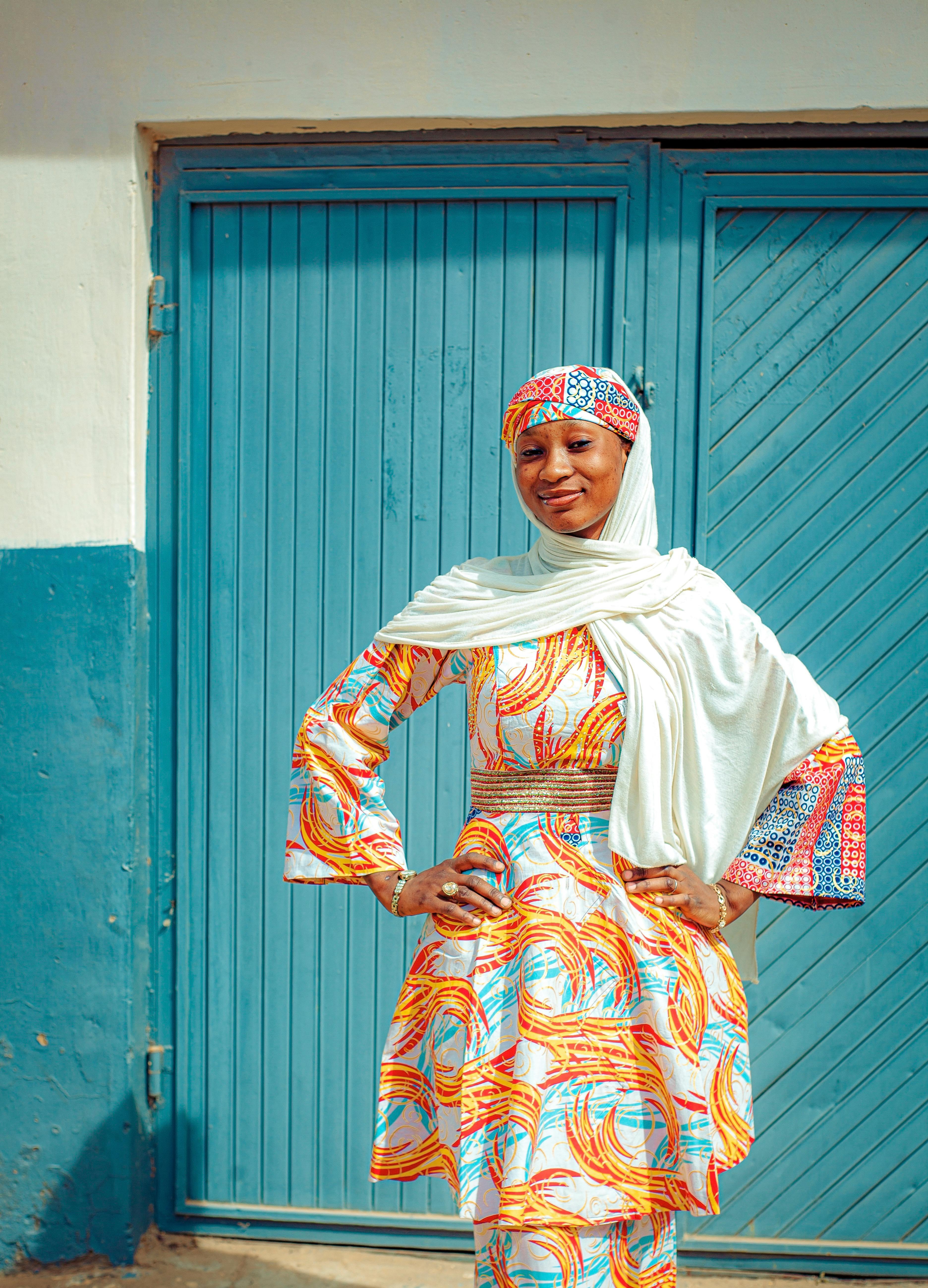 De franc Una dona segura de si mateixa amb un vestit tradicional vibrant posa a fora, al costat d'una porta blava. Foto d'estoc