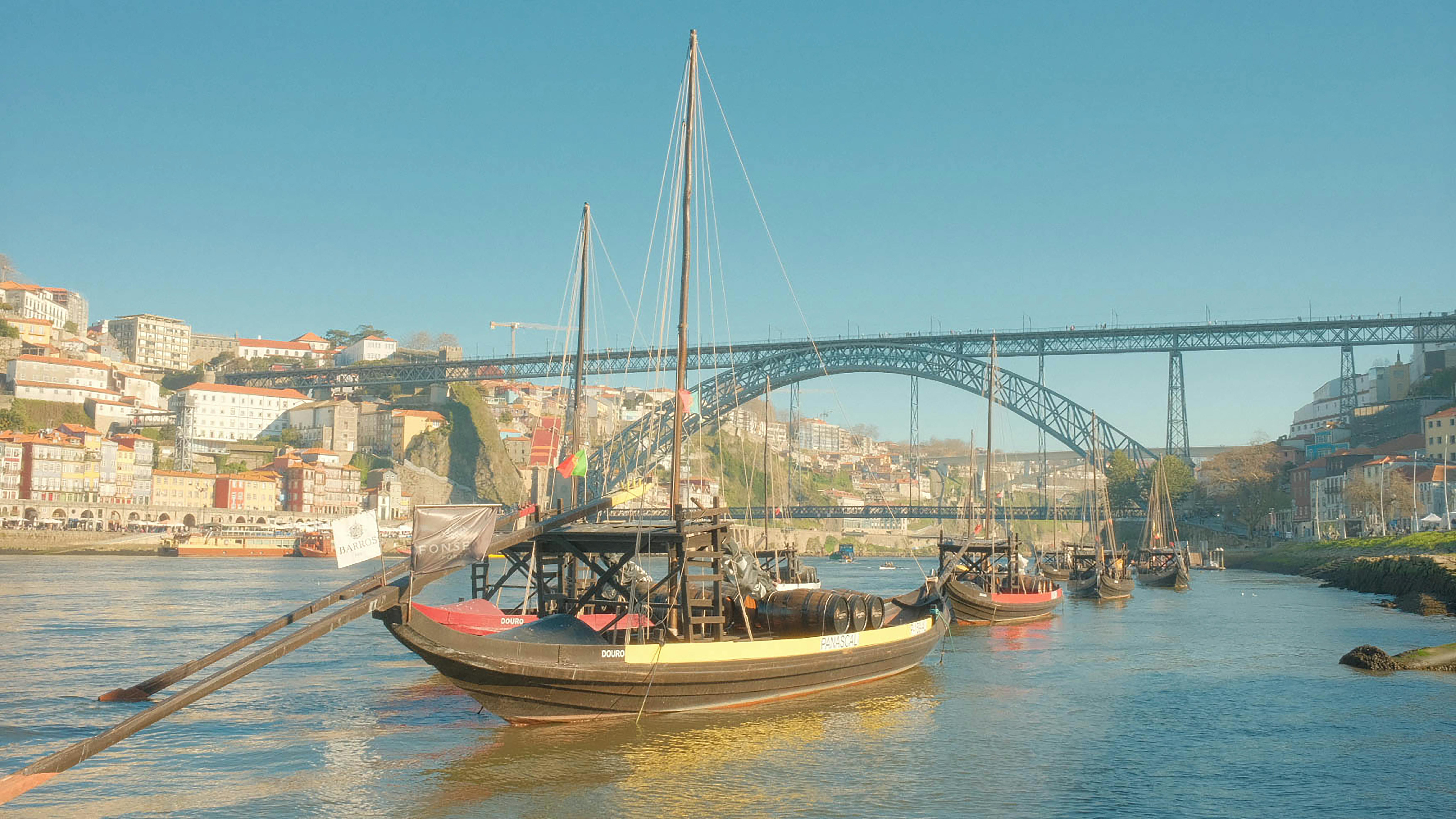 Rabelo boats anchored on Douro River with Dom Luís I Bridge in the background, Porto, Portugal.