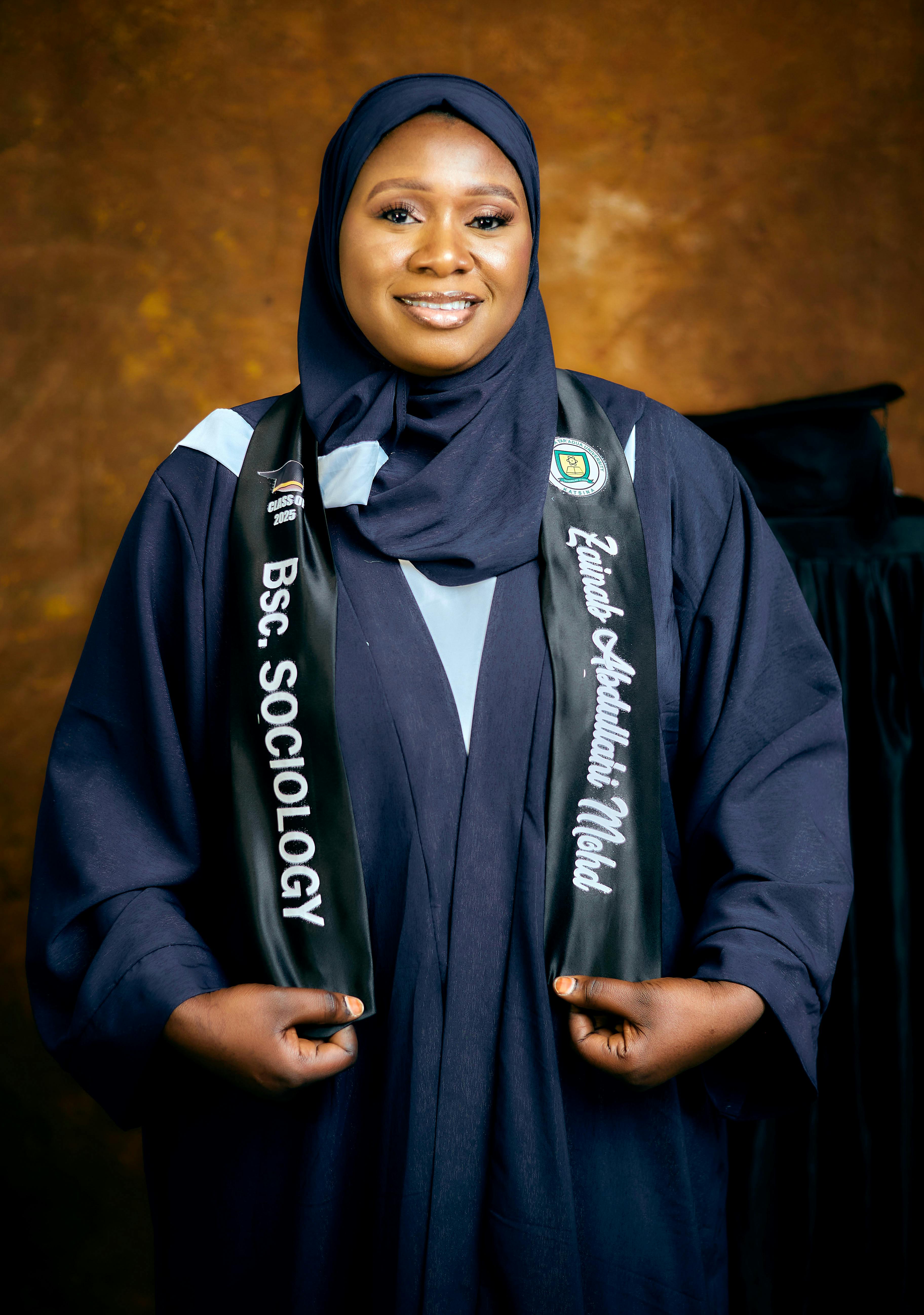 Cheerful female graduate in hijab celebrating with sociology degree.