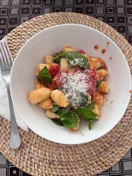Delicious homemade gnocchi topped with fresh tomato sauce, spinach, and grated cheese.