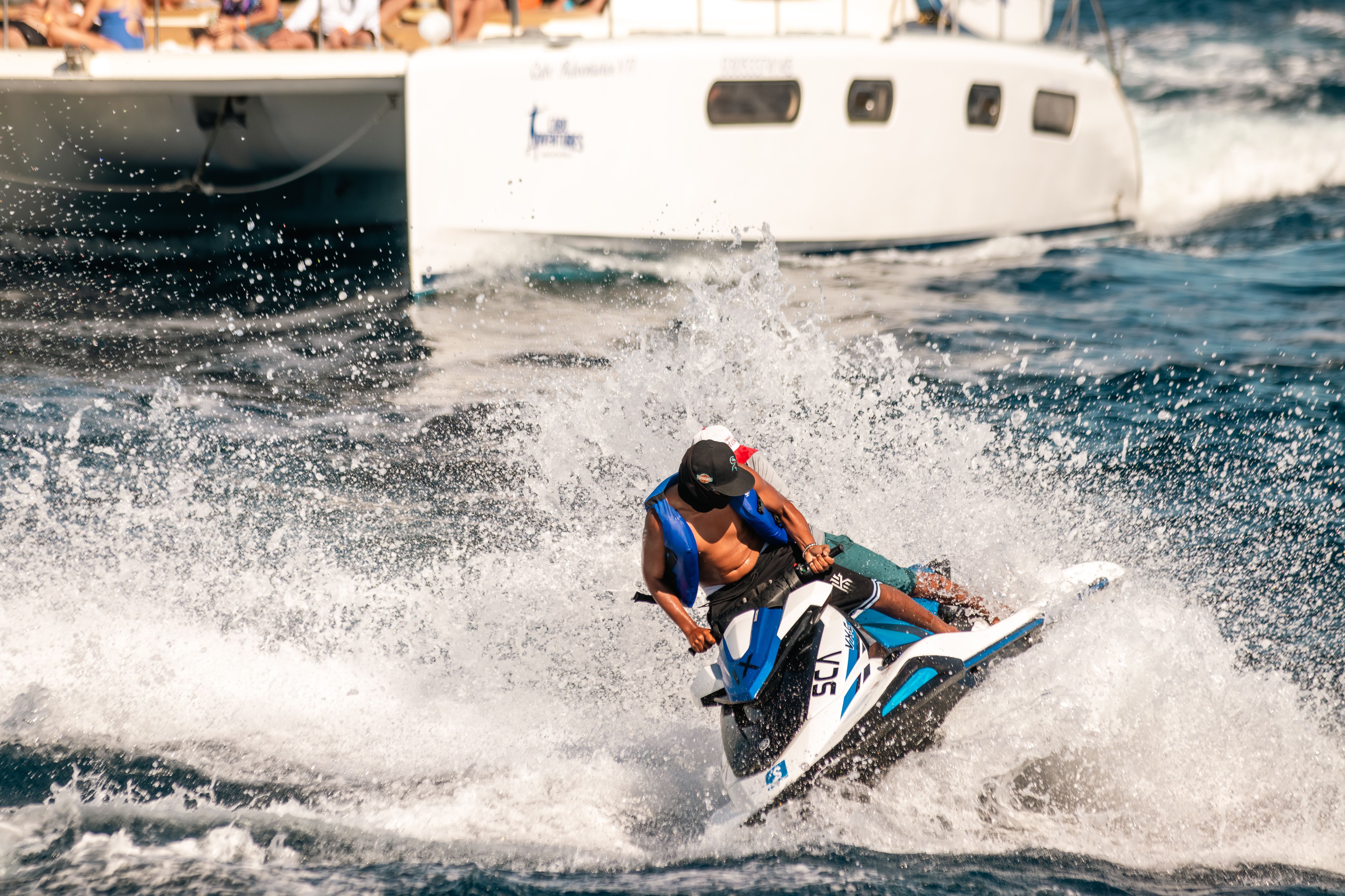 Thrilling jet skiing experience in the vibrant seas of Cabo San Lucas with a yacht in the background