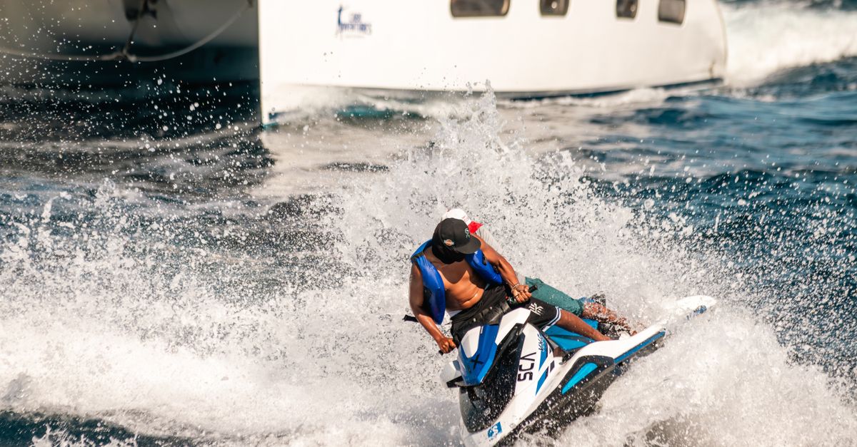 Thrilling jet skiing experience in the vibrant seas of Cabo San Lucas with a yacht in the background