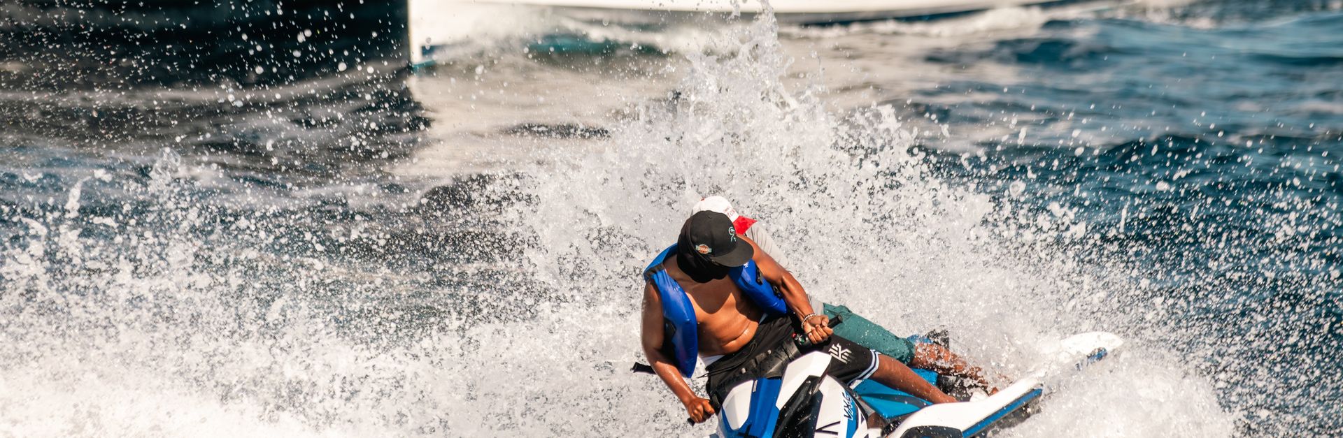 Thrilling jet skiing experience in the vibrant seas of Cabo San Lucas with a yacht in the background