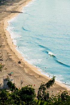 Aerial shot of a sandy beach with people enjoying the waves, offering perfect summer vibes.