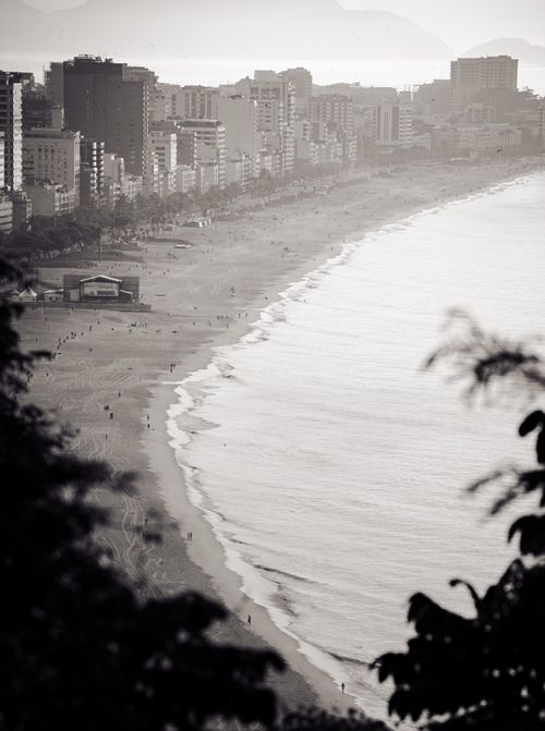 Free A moody black and white photo of a coastal cityscape, featuring a beach and high-rise buildings. Stock Photo