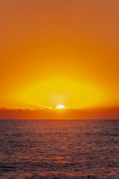 Stunning sunset in Akumal, Quintana Roo, Mexico, with vibrant orange sky over ocean waves.