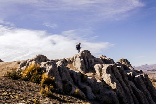 A lone hiker stands atop rocky formations in Arequipa, Peru showcasing adventure and nature's beauty.