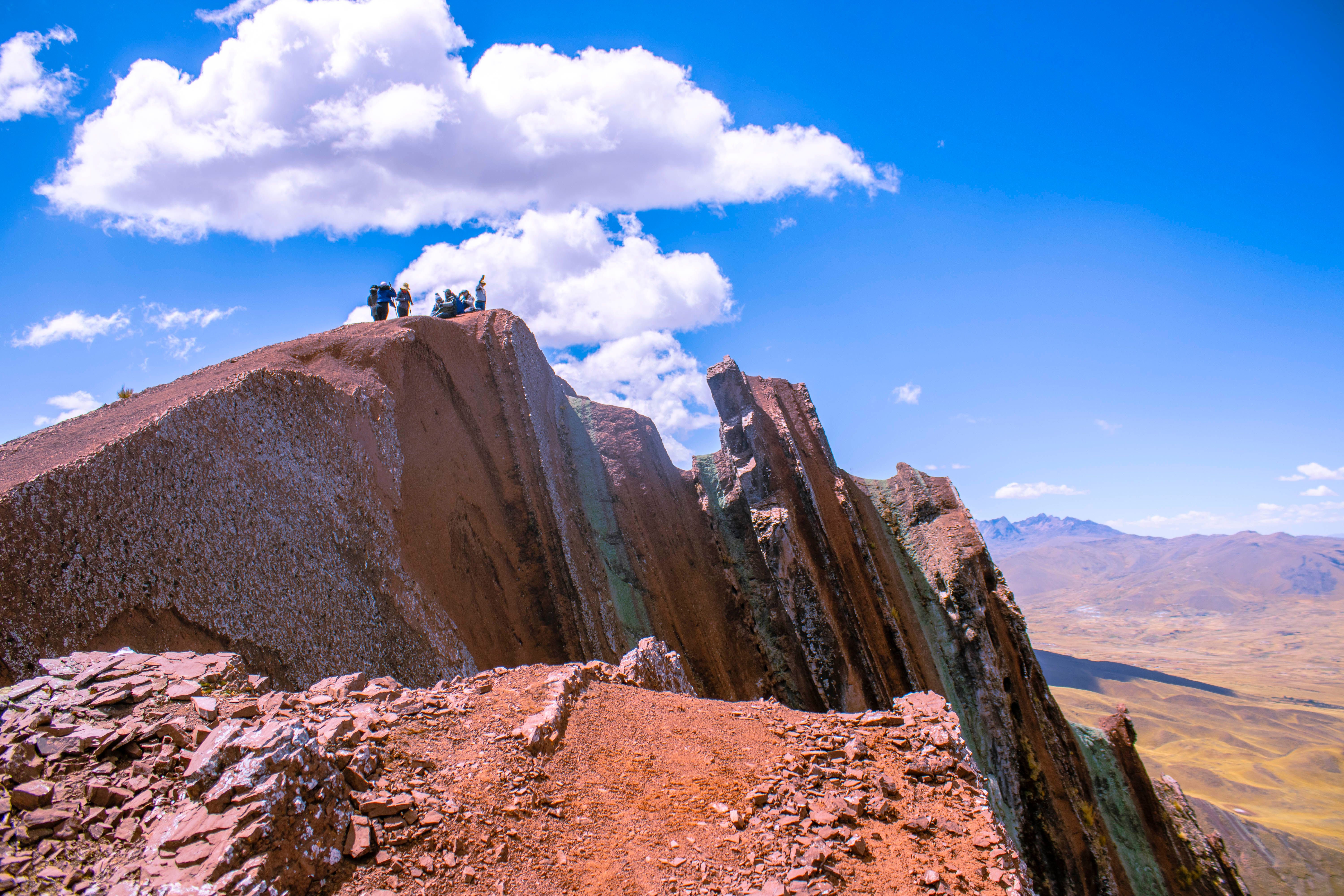Adventurers explore the stunning ridge of Rainbow Mountain in Layo, Cuzco, Peru under a clear blue sky.