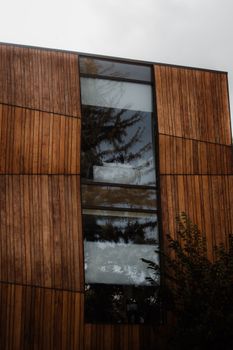 A contemporary building facade with wooden paneling and reflective glass windows.
