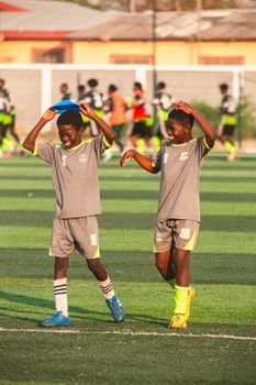Two young soccer players enjoying training on a sunny day with their team in the background.
