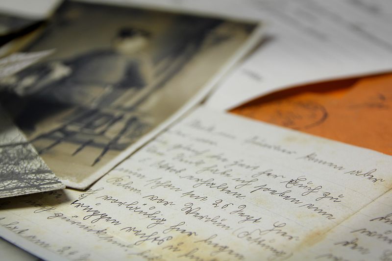 Old handwritten letters and vintage photographs spread on a table, creating a nostalgic feel.