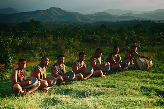 Group of men playing traditional drums in a scenic hilly landscape during the day.