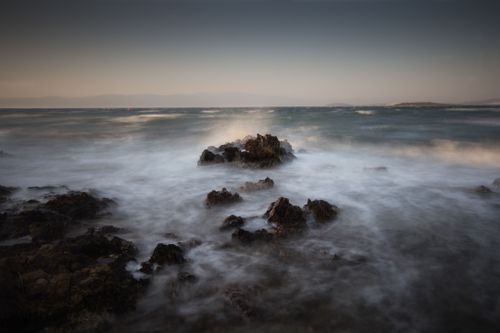 Free Misty coastal scene at dawn, capturing waves crashing on rocks with a tranquil horizon. Stock Photo