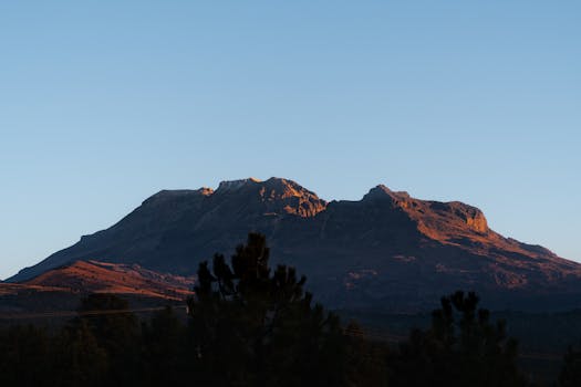 Captivating view of Iztaccihuatl volcano during sunrise with clear blue skies and mountain shadow.