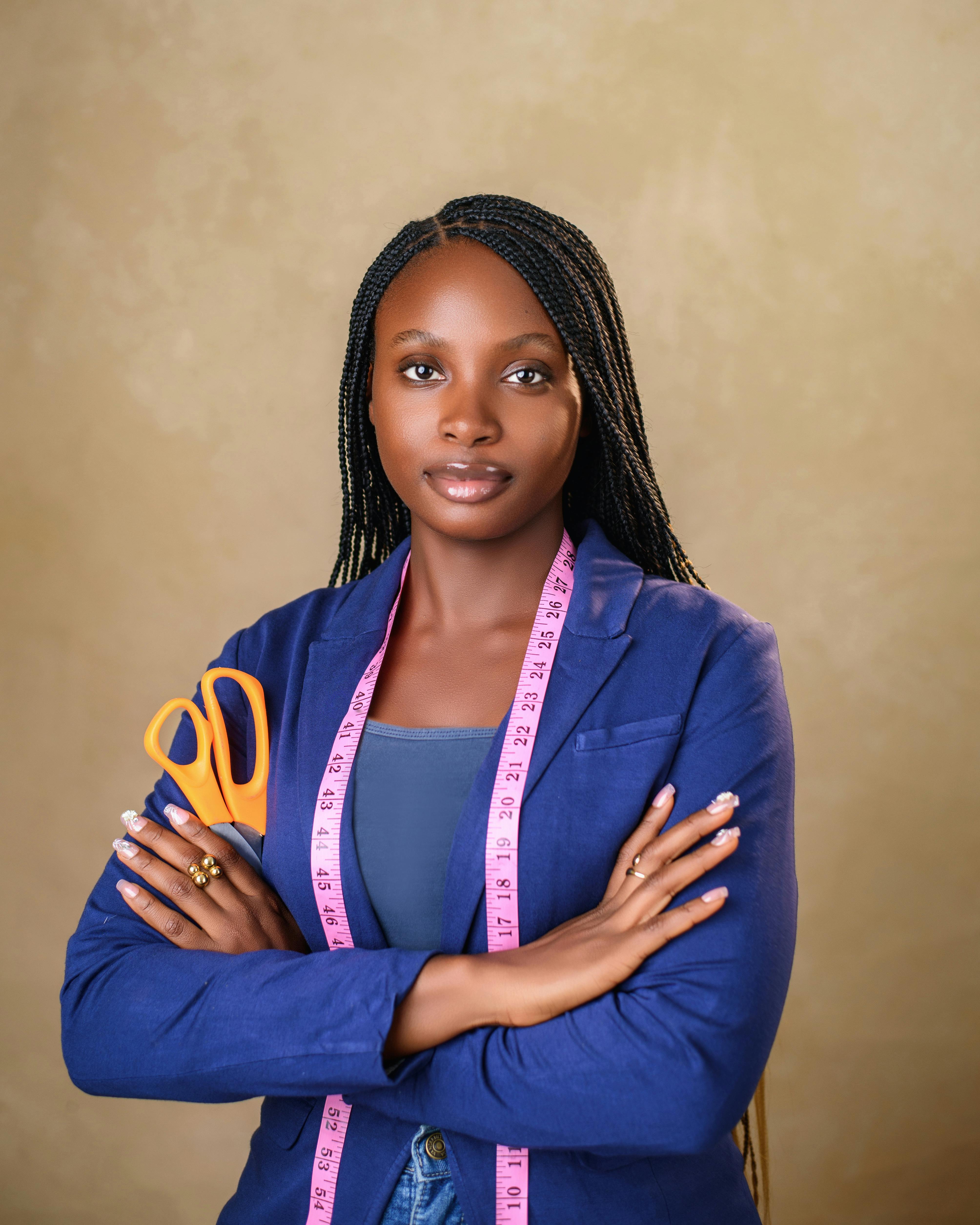 Confident female tailor posing with a measuring tape and scissors, exhibiting style and professionalism.