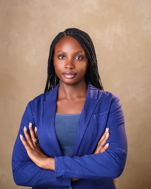 Free Portrait of a confident Black woman in a blue suit with braided hair, arms crossed. Stock Photo