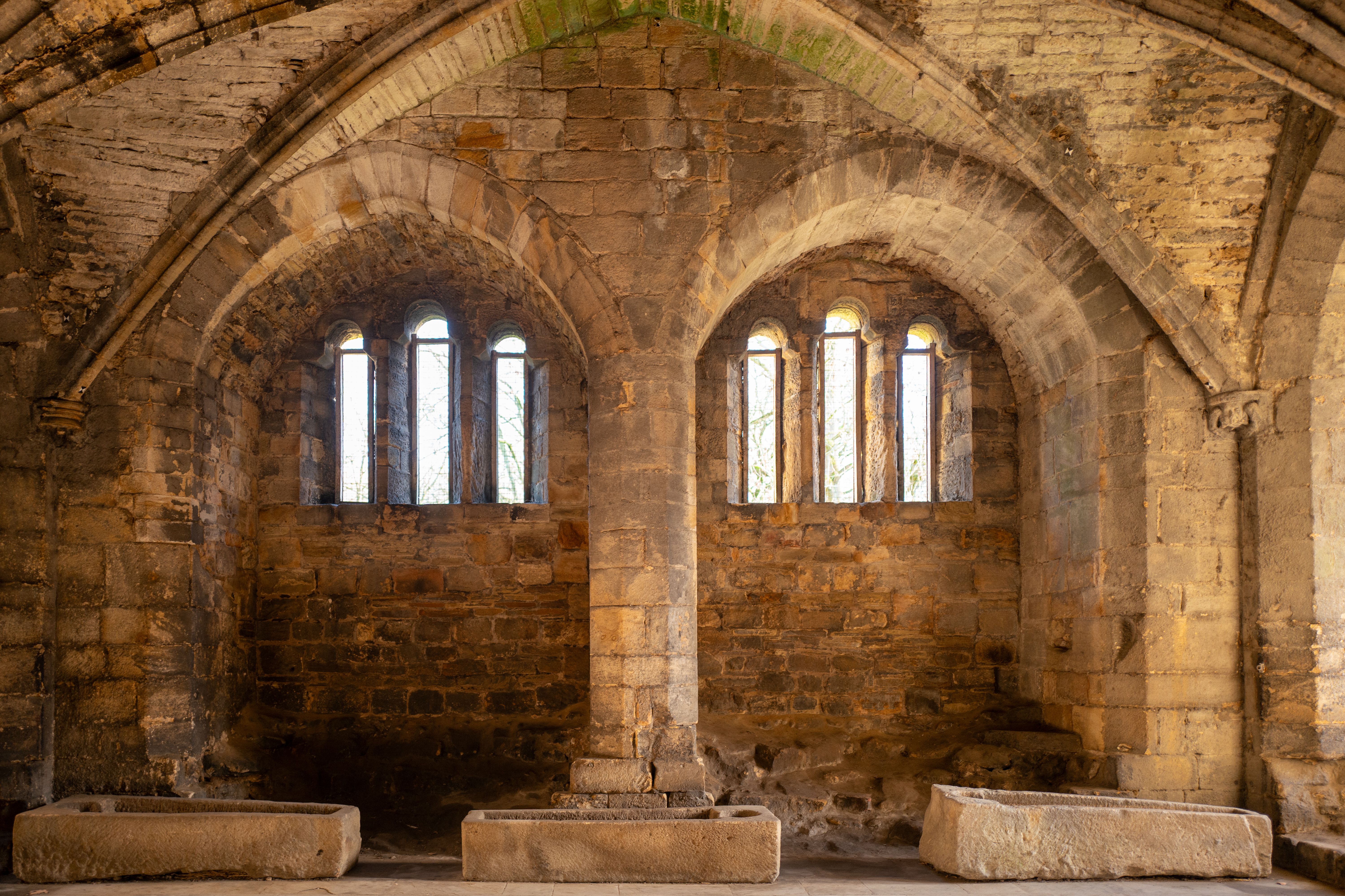 Stone arches and windows in a historic abbey interior in England.