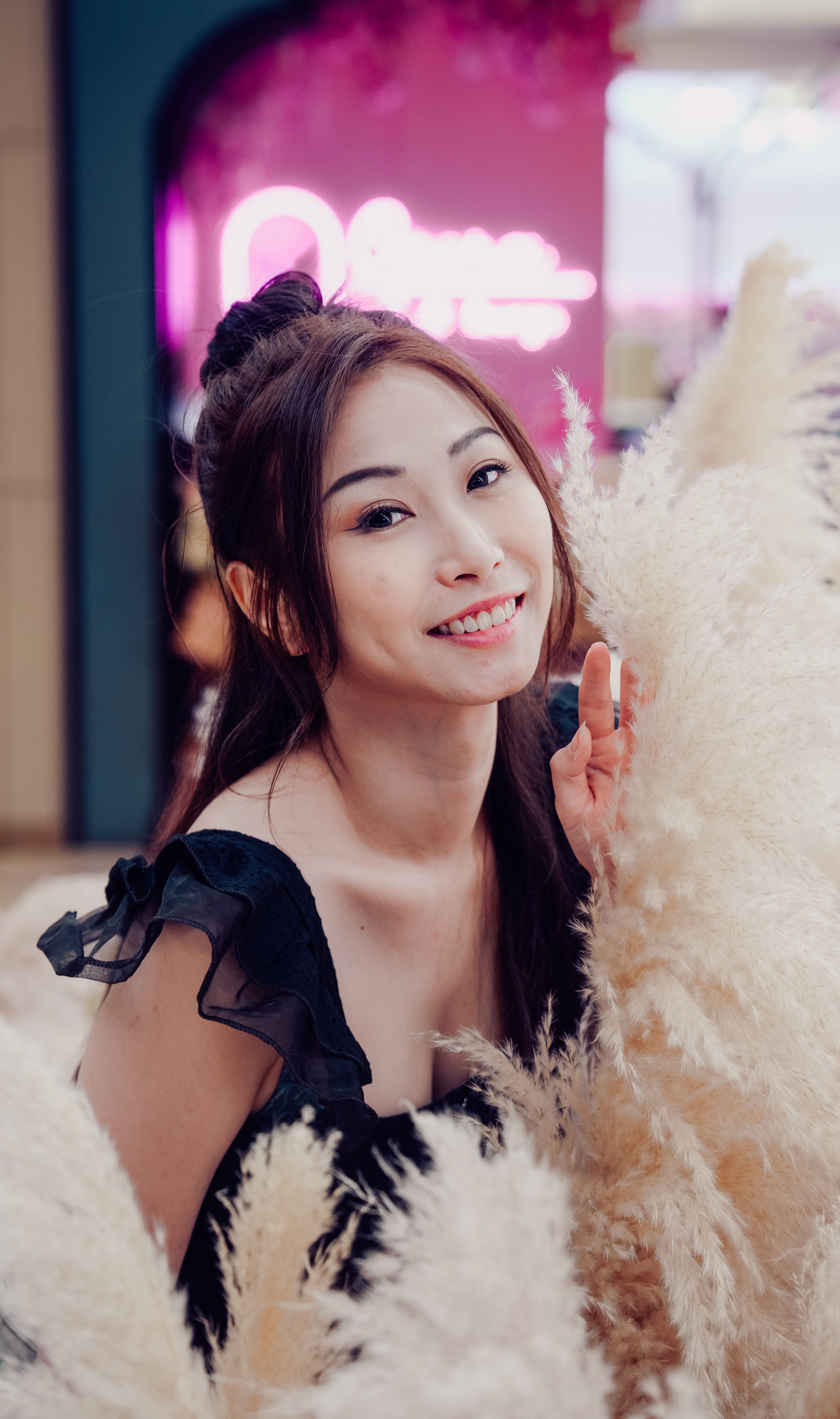 Beautiful woman smiling surrounded by pampas grass, creating a warm and inviting atmosphere indoors.