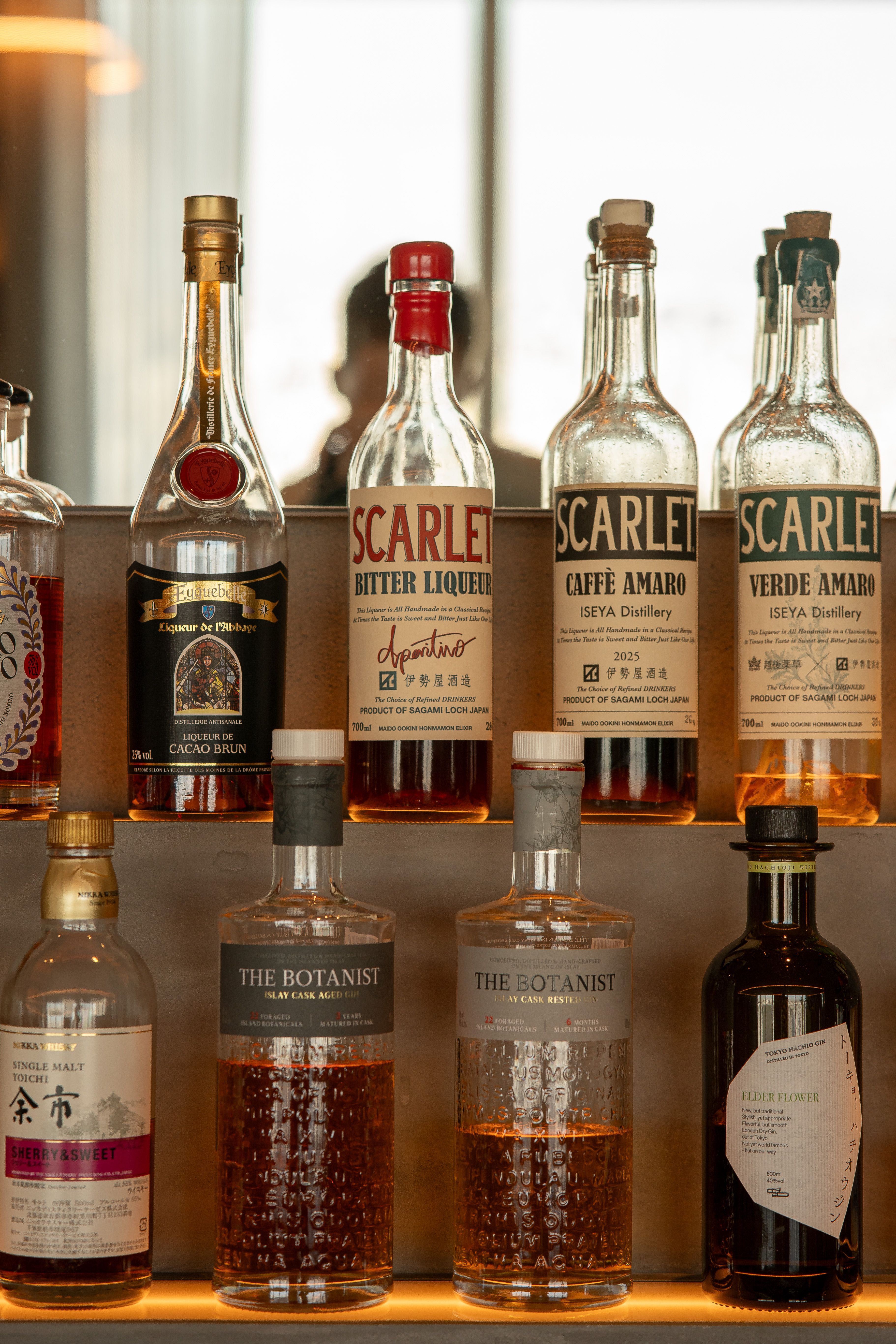 An elegant display of various liquor bottles on a bar shelf in a Tokyo restaurant.