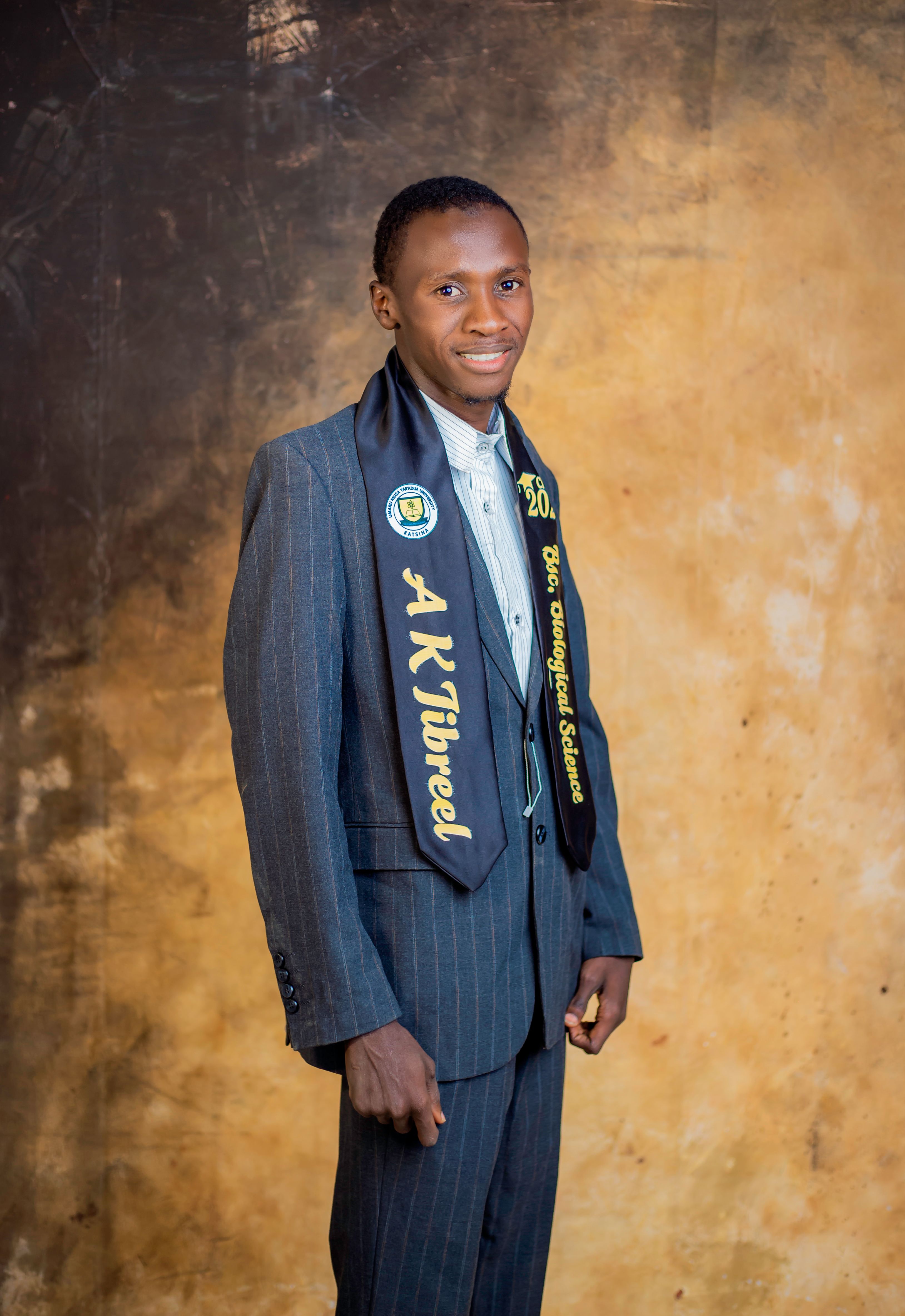 Young adult graduate wearing a suit and sash, celebrating education success.