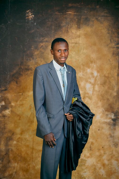 Free A young man in a suit poses confidently against a textured backdrop. Stock Photo