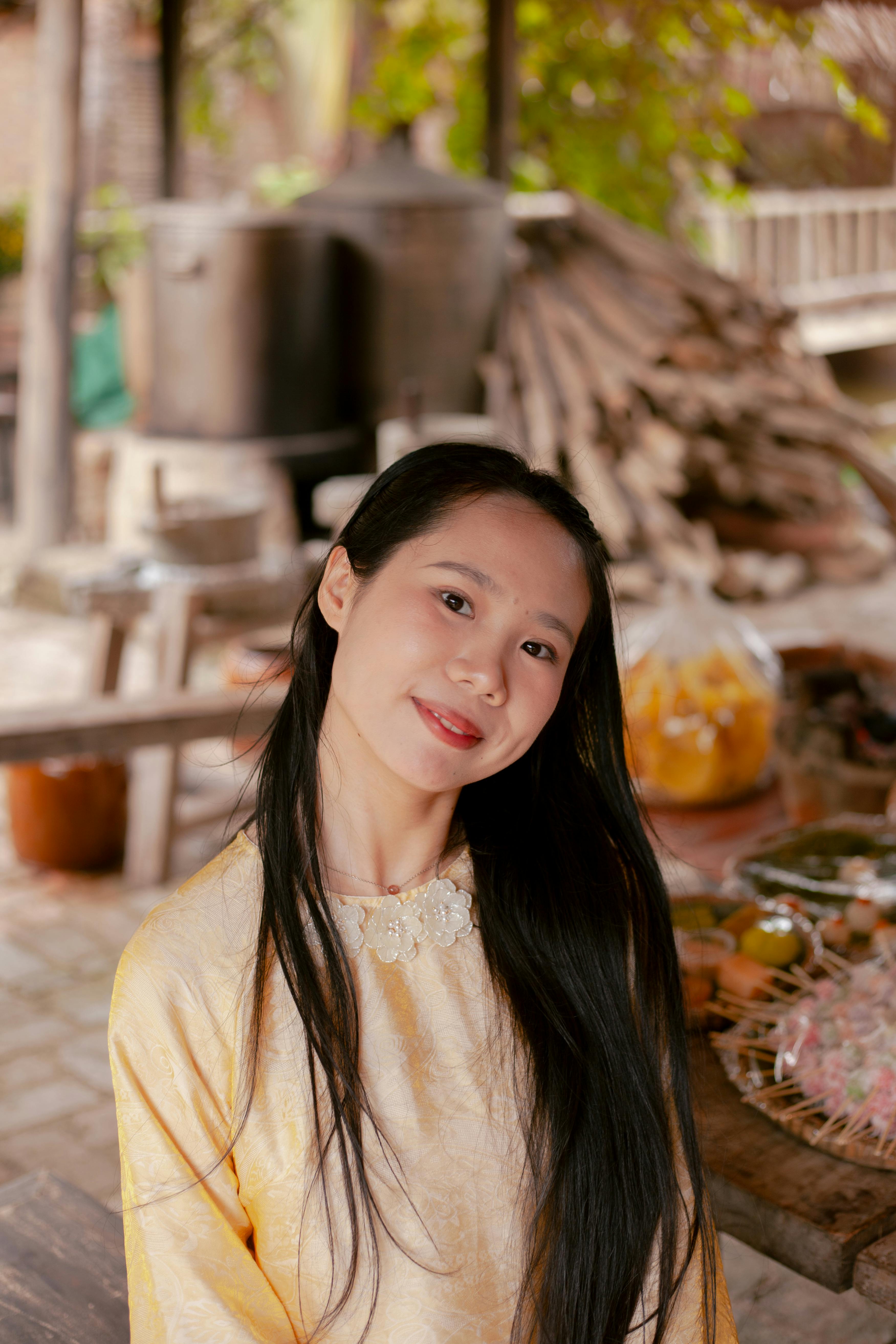 Gratis Una mujer con atuendo tradicional sonríe cálidamente en un entorno al aire libre con decoración rústica. Foto de stock