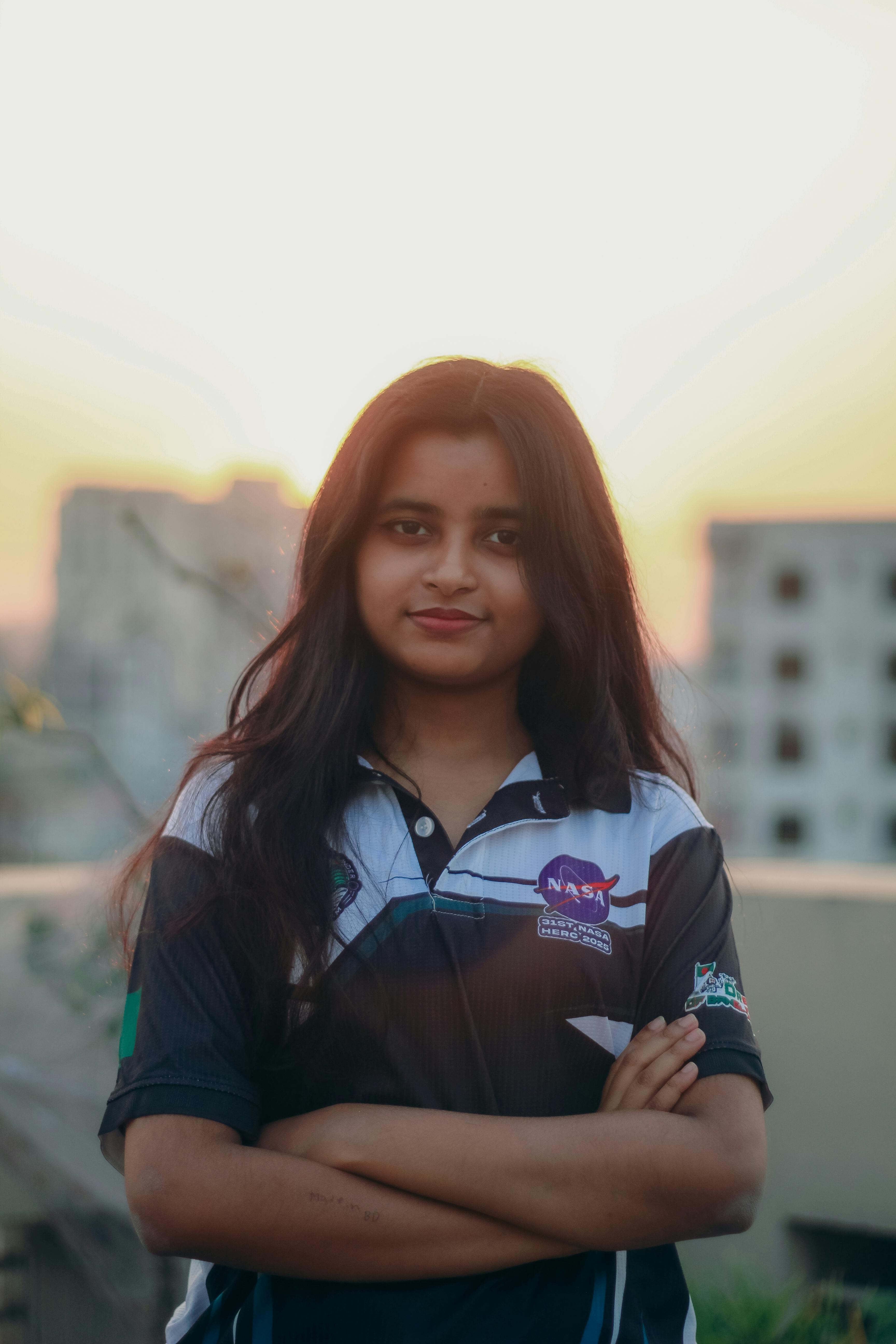 Gratis Retrato de una mujer joven con una camiseta de la NASA con un fondo de paisaje urbano al atardecer en Dhaka, Bangladesh. Foto de stock