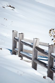 A serene winter scene featuring a wooden fence partially covered in snow, capturing the essence of quiet solitude.